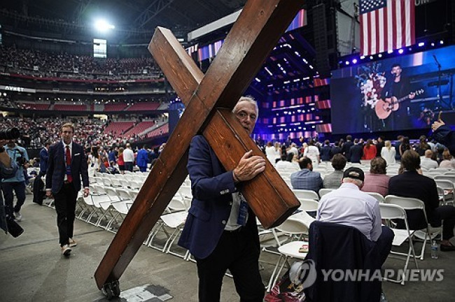 찰리 커크 추모식에 십자가 메고 온 참석자