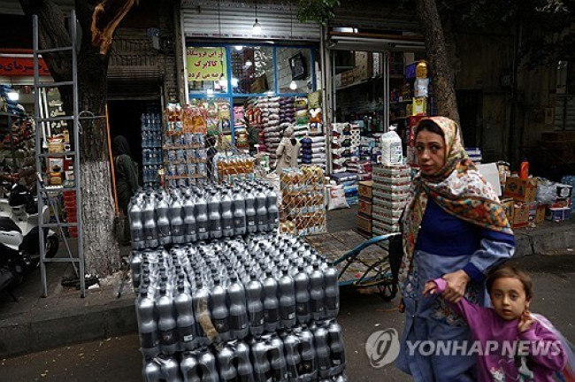 이란 수도 테헤란의 한 상점 앞을 지나는 사람들